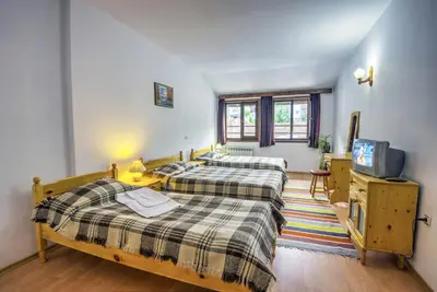 a bedroom with two beds and a tv in it at Hotel Kalina in Shiroka Lŭka