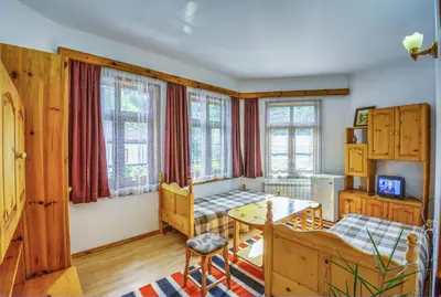 a bedroom with a desk and a table in a room at Hotel Kalina in Shiroka Lŭka