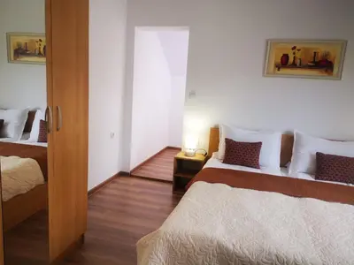 a bedroom with two beds and a table with a lamp at Saint Maria Guest House in Velingrad