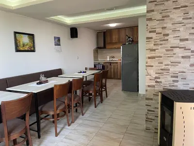 a kitchen and dining room with tables and a refrigerator at Saint Maria Guest House in Velingrad