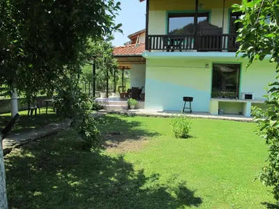 a backyard of a house with a yard with green grass at Pri Orehite Guesthouse in Oreshak