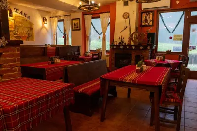 a restaurant with red tables and chairs and a fireplace at Villa Ibar in Borovets