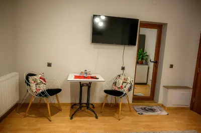 a room with two chairs and a table with a tv on the wall at Guest House Angelkovi in Sapareva Banya