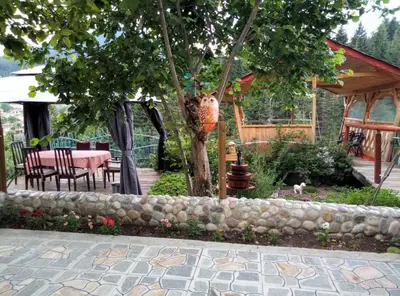 a garden with a table and a tree and a stone wall at Guest House Milka in Yagodina