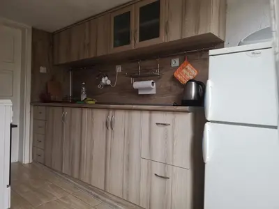a kitchen with wooden cabinets and a white refrigerator at Guest House Milka in Yagodina