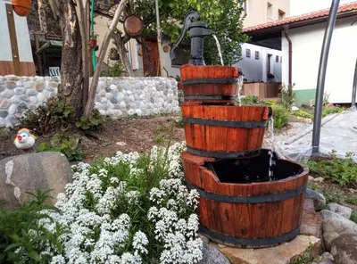 a wooden barrel fountain in a garden with flowers at Guest House Milka in Yagodina