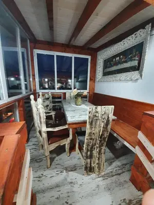 a dining room with a table and chairs and windows at Kashtata s Paraklisa in Borowo