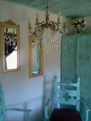 a room with a chandelier and a chair and a mirror at Kashtata s Paraklisa in Borowo