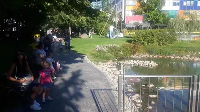 a group of people sitting next to a pond at Business Park Apartment in Sofia