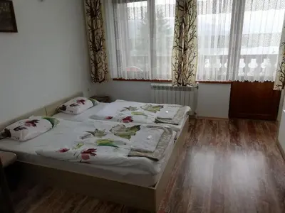a bedroom with a bed in a room with windows at EldoSport Hotel in Dospat