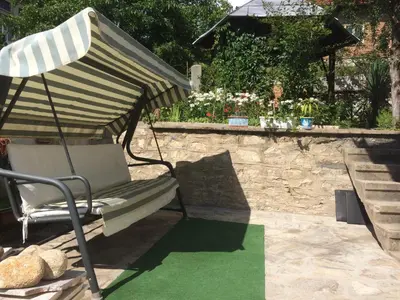 a chair sitting under an umbrella on a lawn at Vila Venera in Velingrad