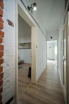 a hallway with a white brick wall and an open door at The Bookies Apartments in Sofia