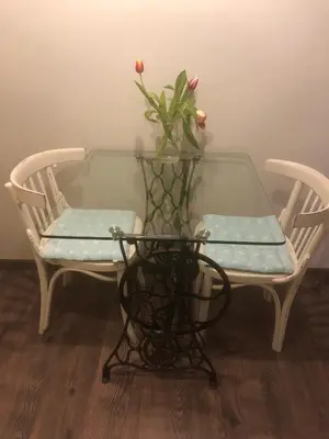 a glass table with two chairs and a vase with flowers on it at The Bookies Apartments in Sofia
