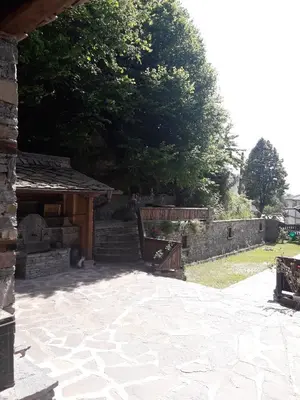 a patio with two benches and a stone wall at Kyshta za Gosti Gospodevi in Gorno Dryanovo