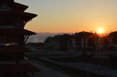 a sunset in a city with buildings in the foreground at Pine Tree Apartment D34 in Bansko