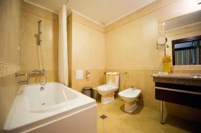 a bathroom with a tub and a toilet and a sink at Grand Hotel Hebar in Pazardzhik