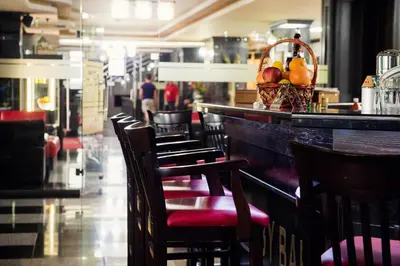 a row of chairs at a bar with a basket of fruit at Grand Hotel Hebar in Pazardzhik