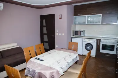 a living room with a table and a couch and a kitchen at Apartment Ira in Velingrad