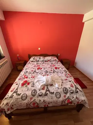 a bedroom with a bed with a red wall at Yovkovata Kyshta in Chiflik