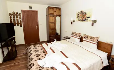 a bedroom with a bed with white sheets and a tv at Guesthouse Nefertiti in Smolyan