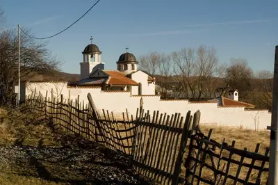 a building with a fence and a church in the background at Вила Бойковец in Boykovets