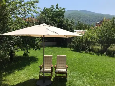 two chairs under an umbrella in the grass at Guest House Vergie, Fully Private in Sapareva Banya