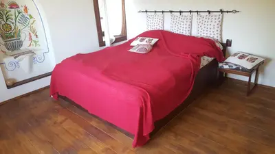 a bed with a red blanket on top of it at Pisanata House in Dedovo
