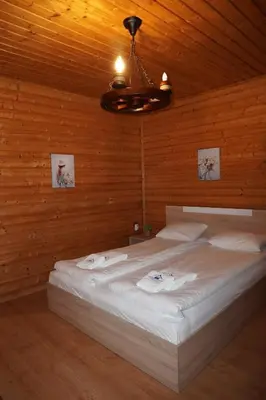 a bedroom with a bed with white sheets and a ceiling at Planinski Polah House in Devin