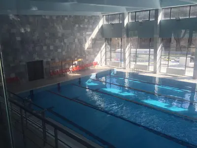 a large swimming pool with blue water in a building at Guest Apartment Monarch in Smolyan