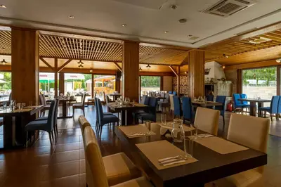 a dining room with tables and chairs and windows at The Balkan Jewel Resort, Trademark Collection by Wyndham in Bansko
