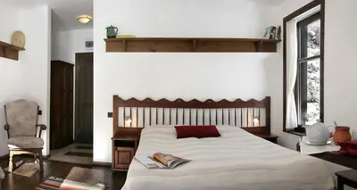 a bedroom with a large bed and a chair at Family Hotel Arkan Han in Trigrad