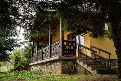 a yellow house with a porch with stairs and flowers at Бунгала Дара in Kalofer