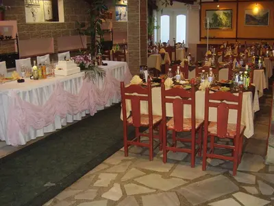 a dining room with tables with white tablecloths and chairs at Kestenite Family Hotel in Samokov