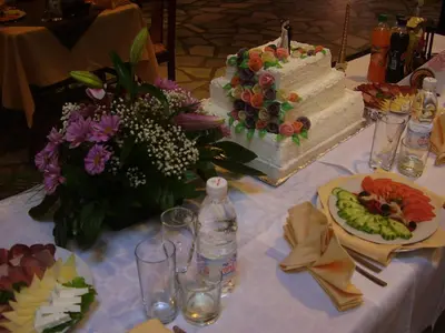 a table with a wedding cake and flowers on it at Kestenite Family Hotel in Samokov