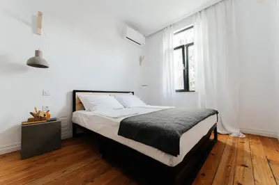 a bedroom with a bed with white walls and wooden floors at Mouse House Kapana in Plovdiv