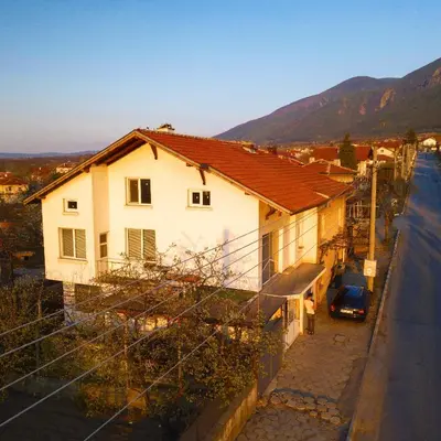 a white house with a car parked next to a street at Apartment Diana in Resilovo