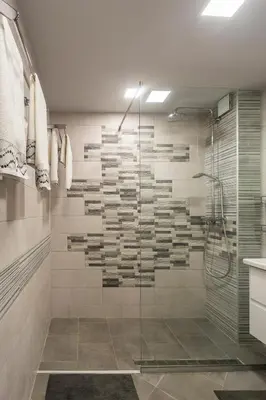 a bathroom with a glass shower with books on the wall at Vacation Apartment in Plovdiv
