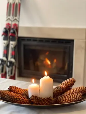 two candles on a plate in front of a fireplace at Grand Monastery Private Apartments in Pamporovo