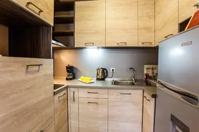 a kitchen with wooden cabinets and a stainless steel refrigerator at Sofia Place Hotel by HMG in Sofia