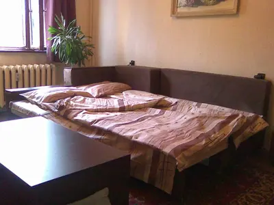 an unmade bed in a room with a table at Top Place in Downtown in Sofia