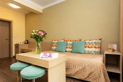 a room with a bed with a vase of flowers on a table at Geneva Hotel in Sofia