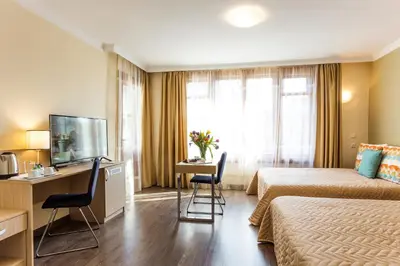a hotel room with two beds and a desk and a television at Geneva Hotel in Sofia