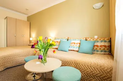a hotel room with a bed with a vase of flowers on it at Geneva Hotel in Sofia