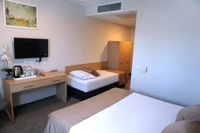 a room with two beds and a desk and a tv at Hotel Ihtiman in Ikhtiman