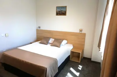 a small bedroom with a bed with white sheets at Hotel Ihtiman in Ikhtiman
