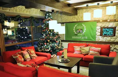 a living room with a christmas tree and red couches at Pirin River Ski, Fun and Family in Bansko