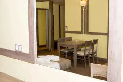 a room with a table and chairs and a mirror at Hotel Etropolia in Etropole