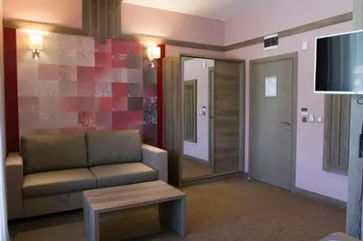 a living room with a couch and a television at Hotel Etropolia in Etropole