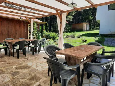 a patio with tables and chairs under a wooden pergola at Villa Sveti Dimitar in Borovets