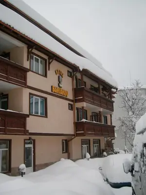 a building with a sign on it in the snow at Bariakov Family Hotel in Bansko